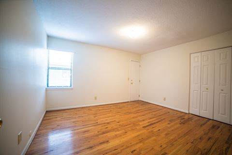 the living room of an empty home with wood floors and white walls