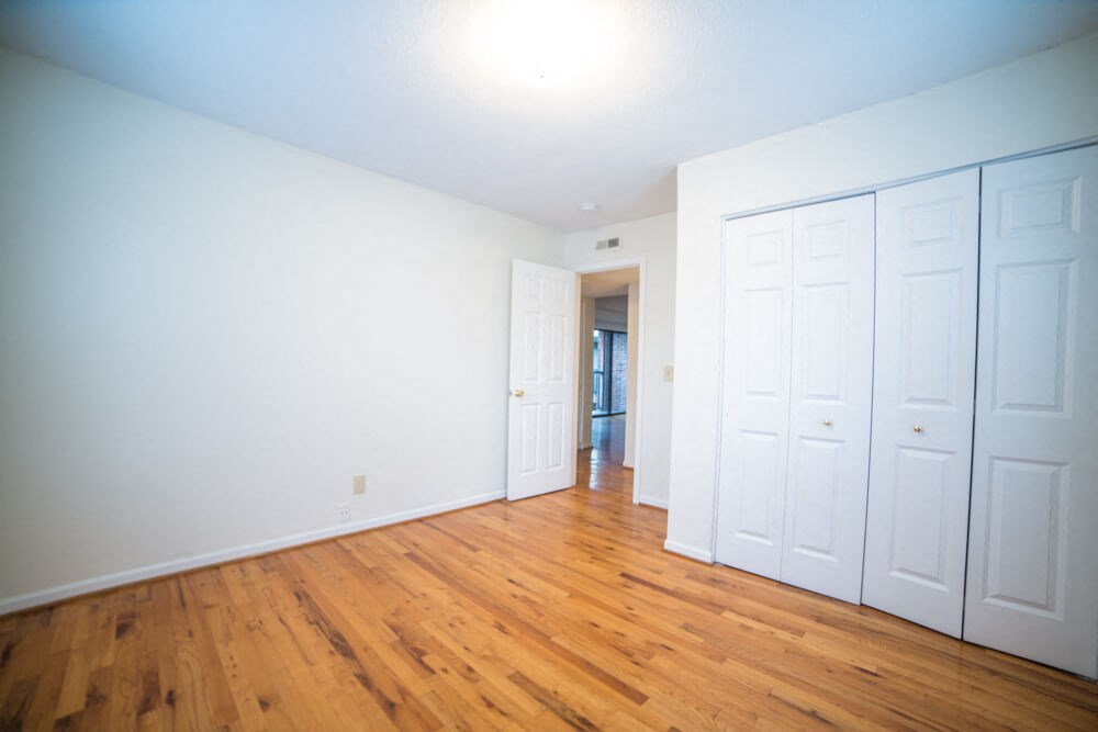 an empty room with white closets and wood floors
