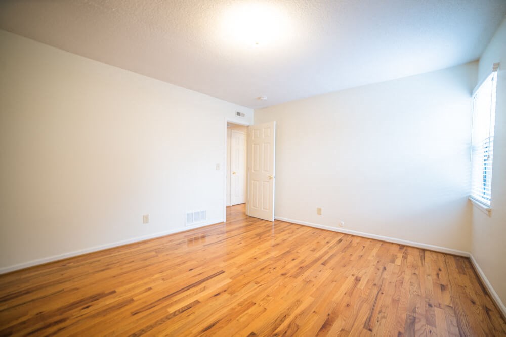 an empty living room with wood floors and white walls