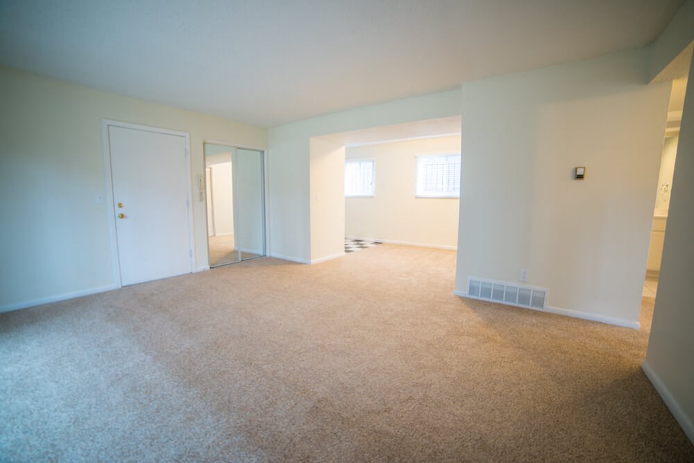 an empty living room with white walls and carpet