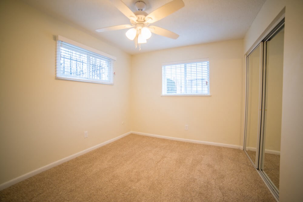 a bedroom with a ceiling fan and a mirrored closet