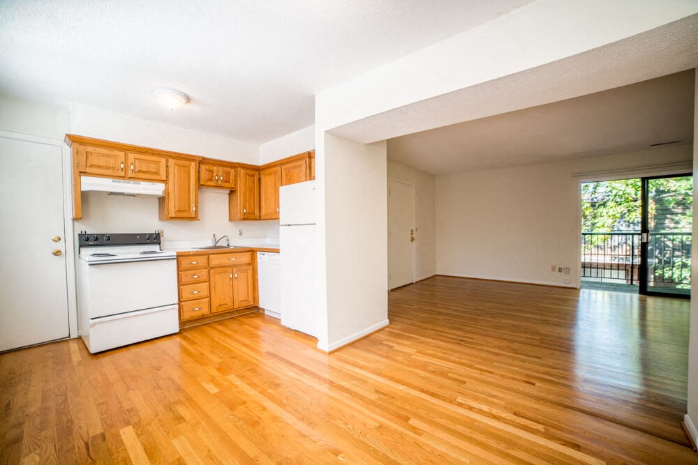 an empty kitchen and living room with wood floors