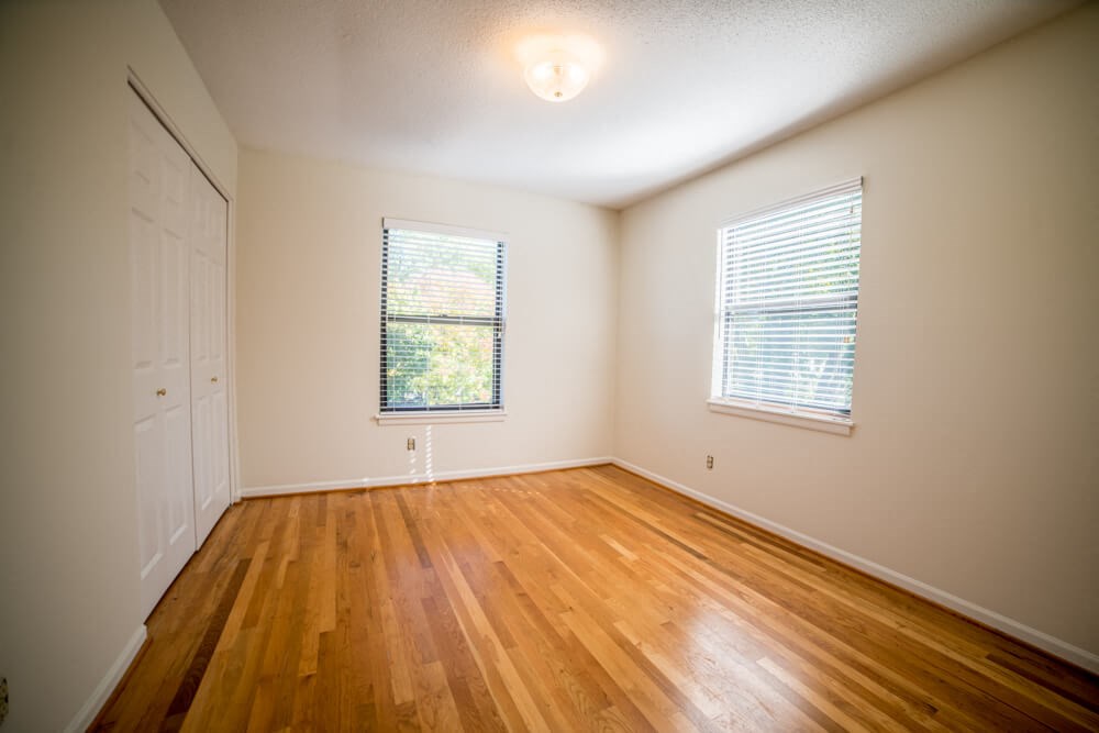 an empty living room with wood floors and white walls