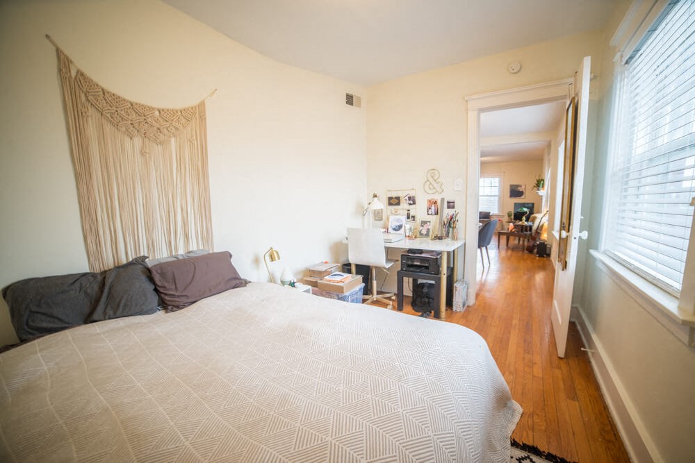 a bedroom with a bed and a living room with a desk