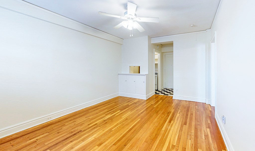 an empty living room with wood floors and a ceiling fan