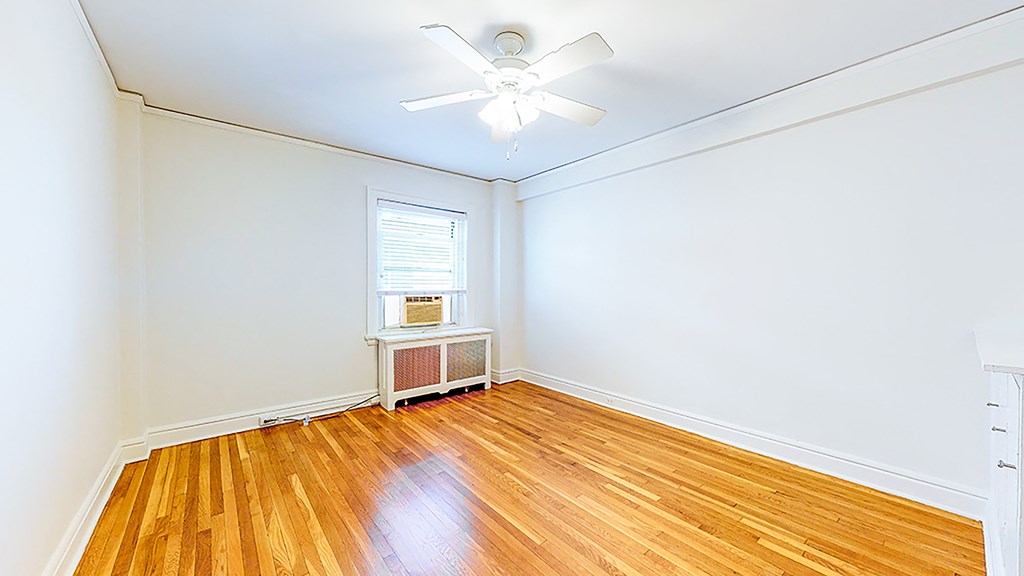 an empty room with wood floors and a ceiling fan