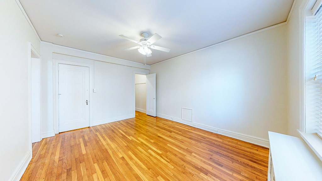 an empty living room with wood floors and a ceiling fan
