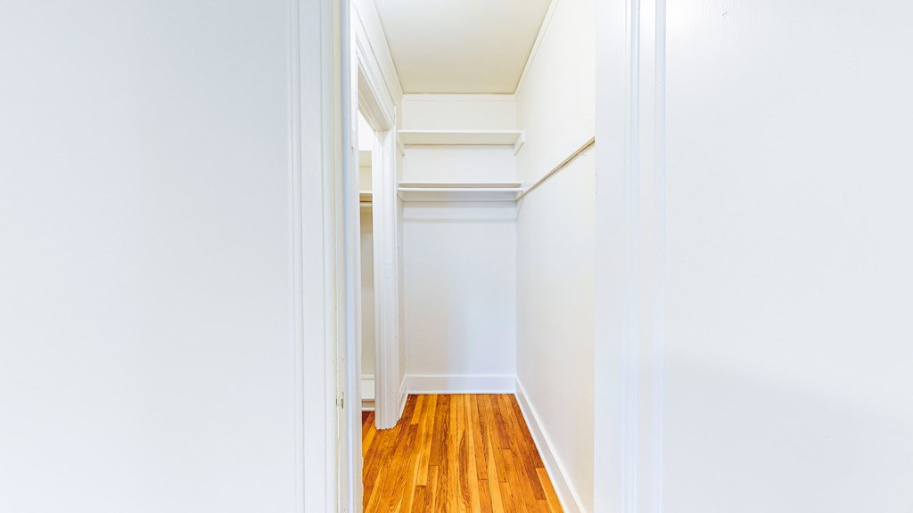 a room with white walls and wood floors and a white closet