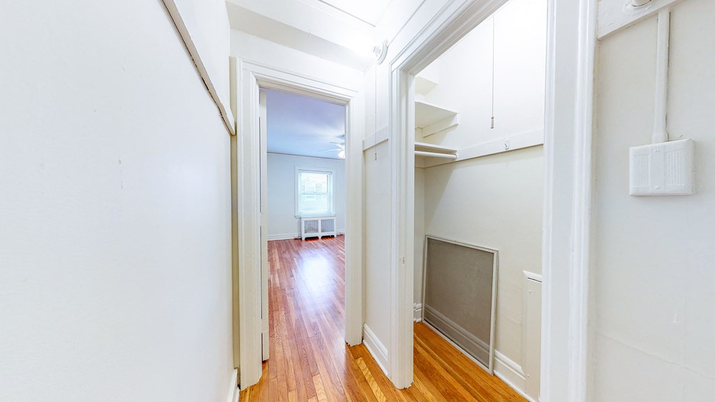 a living room with wood floors and white walls and a doorway