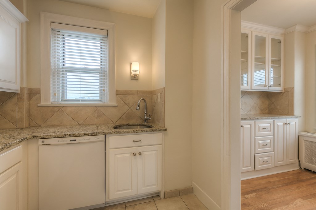 a kitchen with white cabinets and a sink and a window