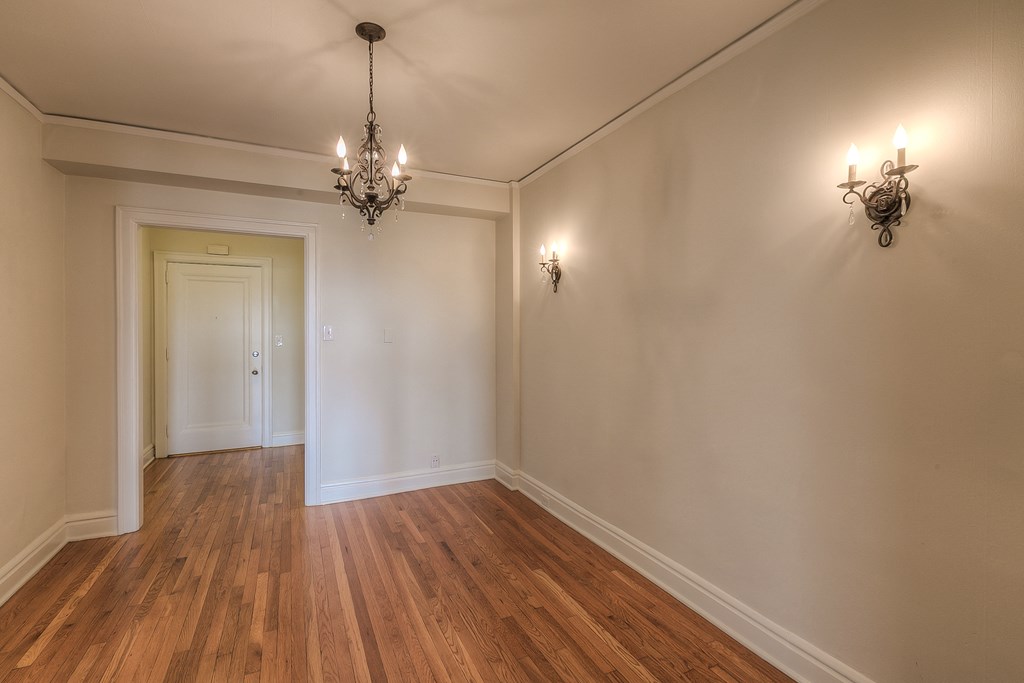 a living room with white walls and wooden floors and a chandelier