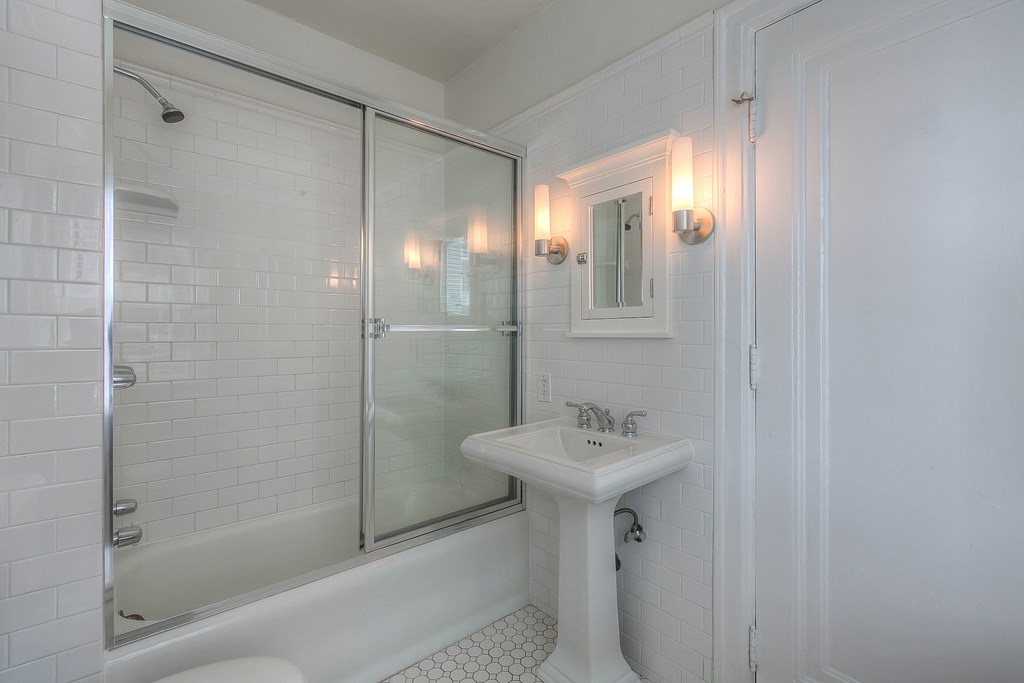 a white bathroom with a sink and a shower