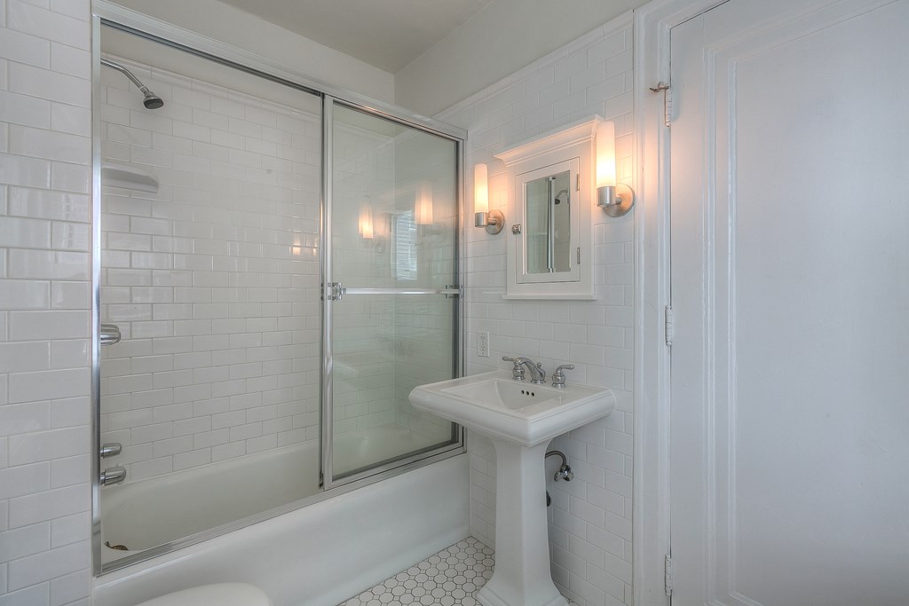 a white bathroom with a sink and a shower
