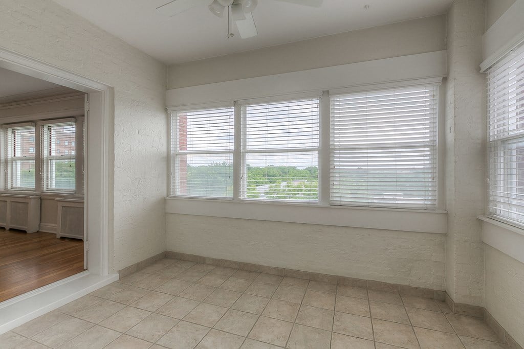 an empty living room with four windows and a tile floor