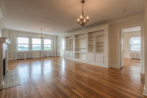 an empty living room with a hard wood floor and white shelves