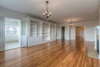 an empty living room with a hard wood floor and white shelves