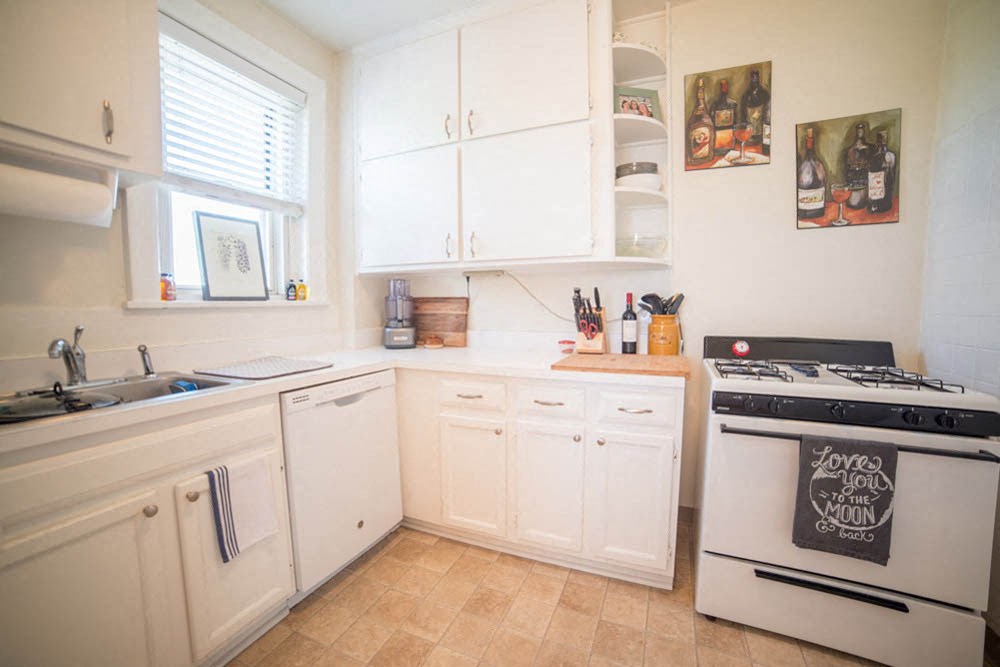 a kitchen with white cabinets and a stove and a sink