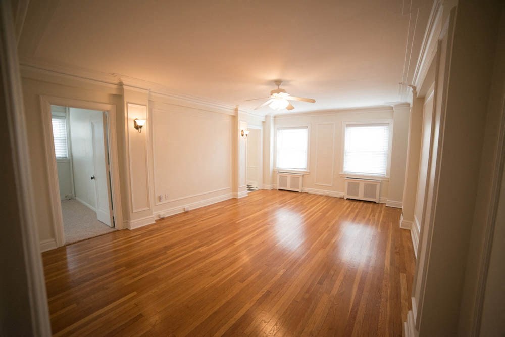 an empty living room with wood floors and a ceiling fan