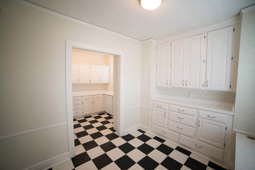 a kitchen with a checkered floor and white cabinets