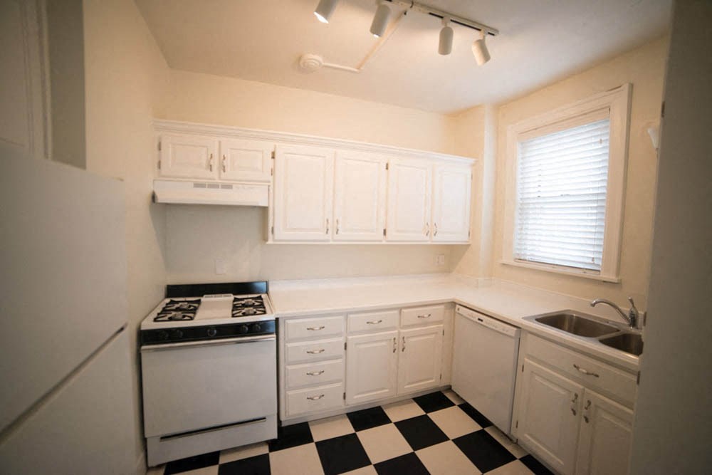 a kitchen with a checkered floor and white cabinets