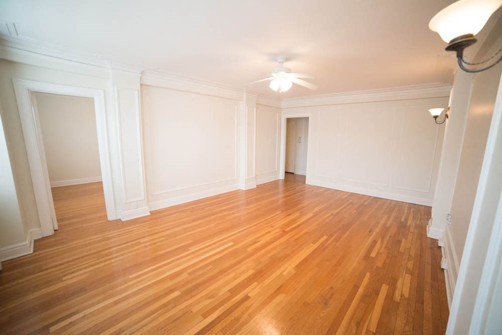 an empty living room with wood floors and white walls
