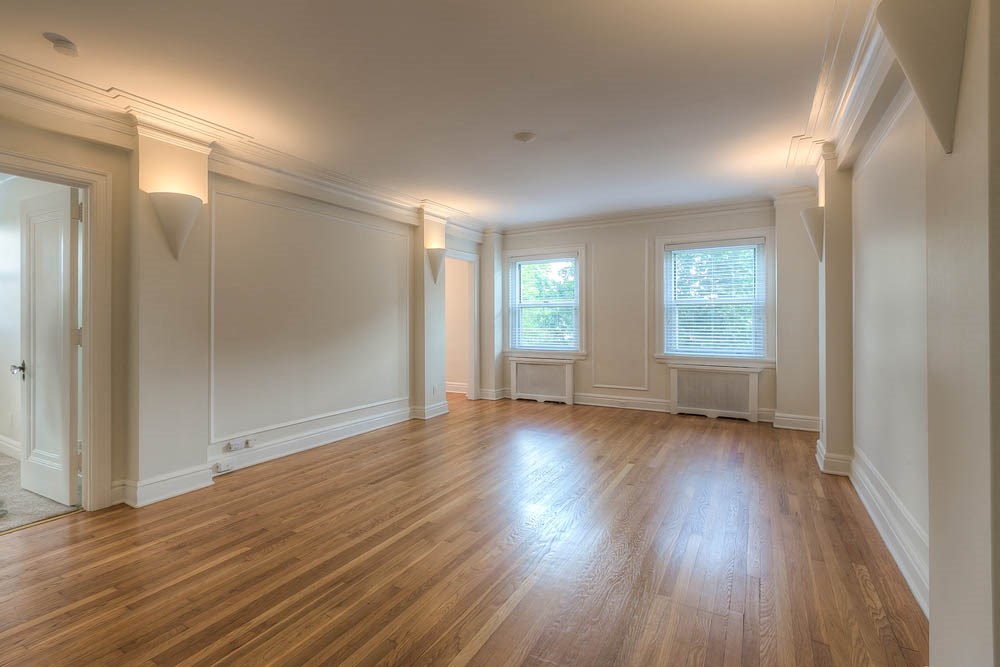 an empty living room with wood floors and white walls