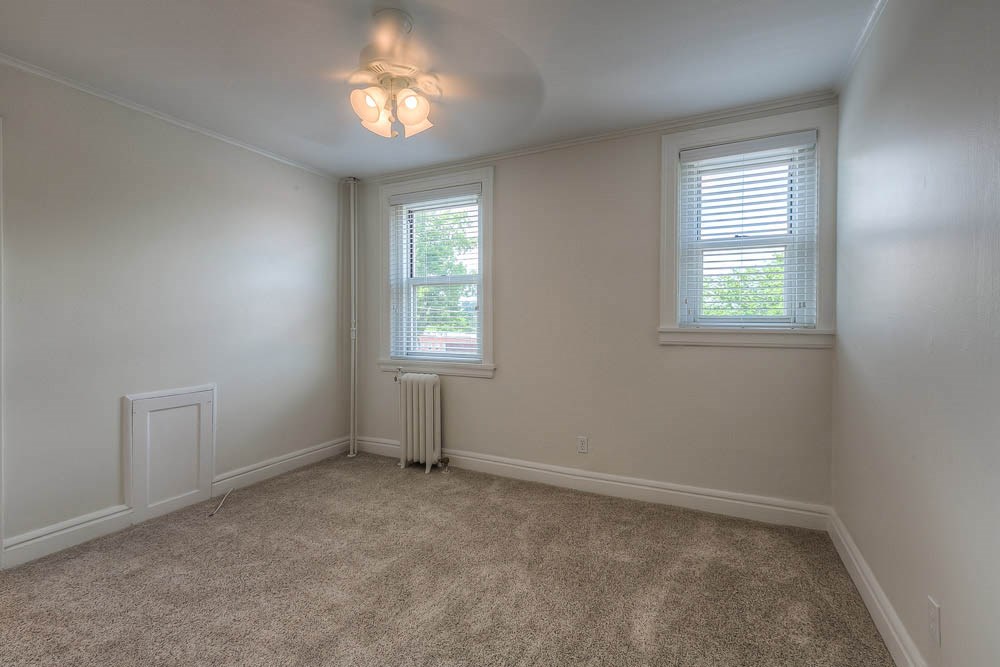 a empty bedroom with two windows and a carpeted floor