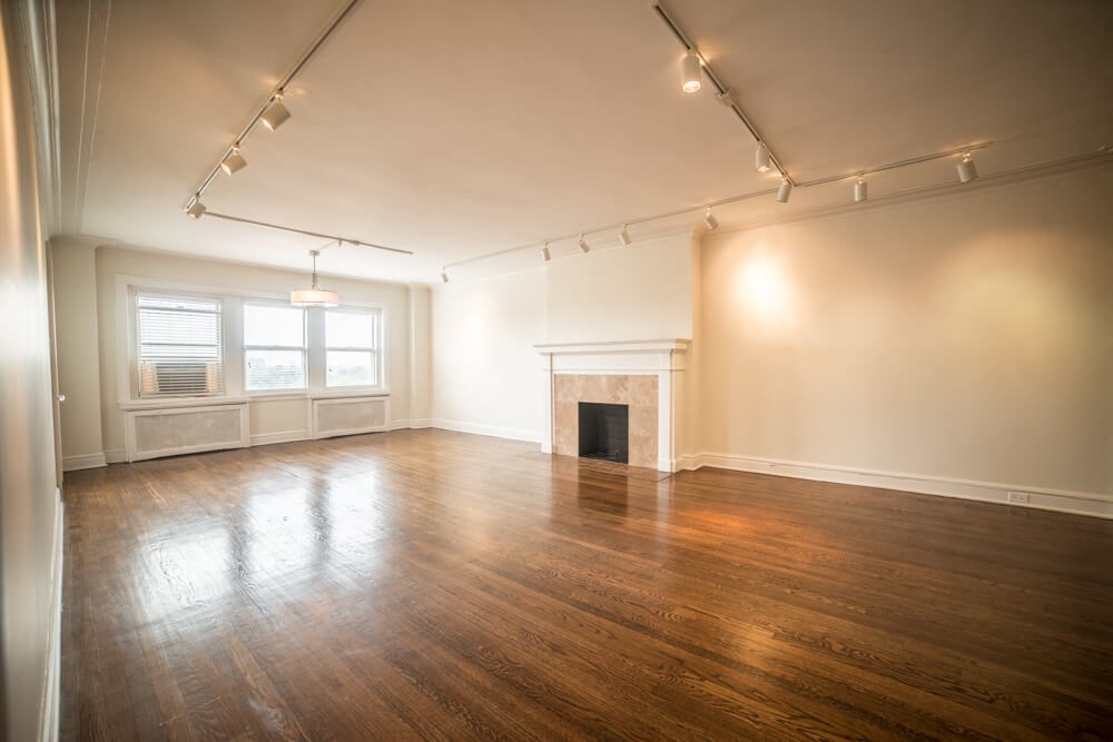 an empty living room with a fireplace and wood floors