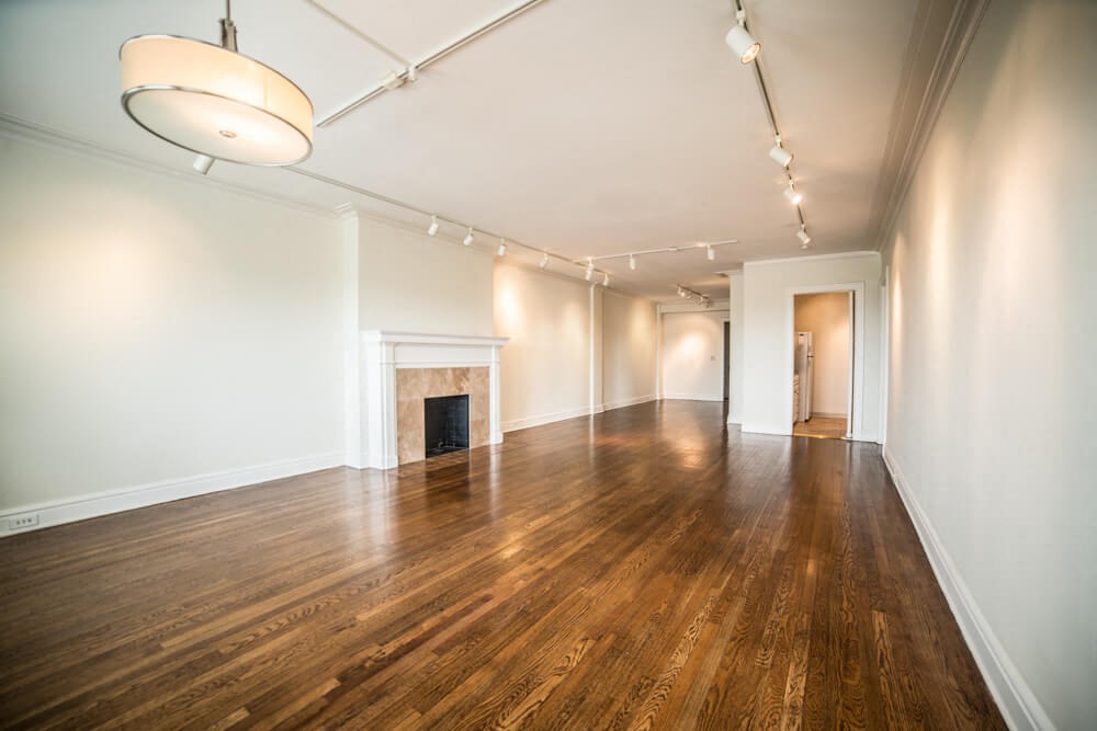an empty living room with a fireplace and wood floors