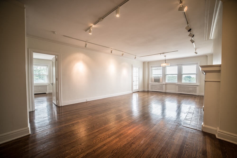 an empty living room with wood floors and white walls