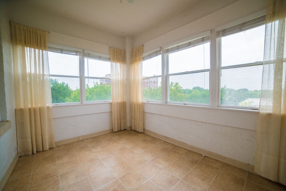 an empty room with three windows with curtains