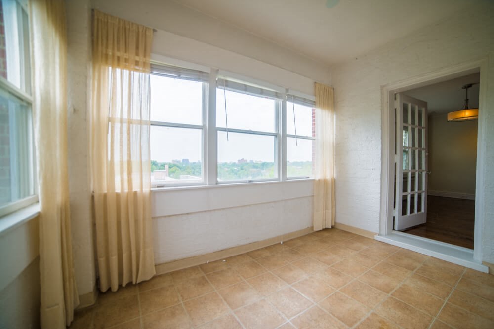 an empty living room with a large window and curtains