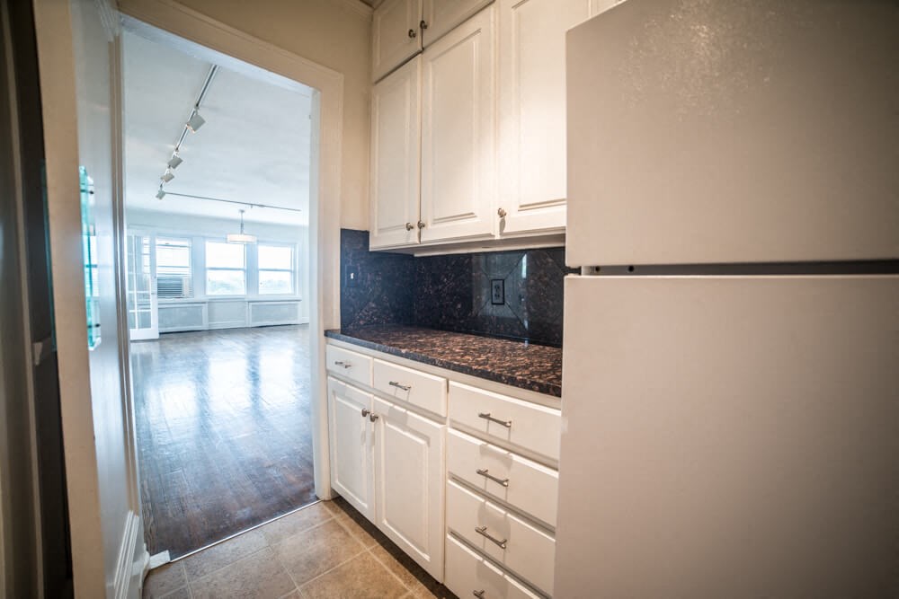 a kitchen with white cabinets and a refrigerator
