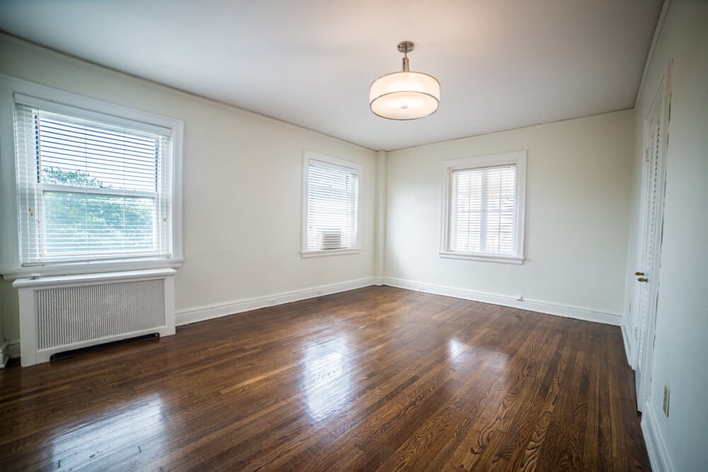 an empty living room with wood floors and a window