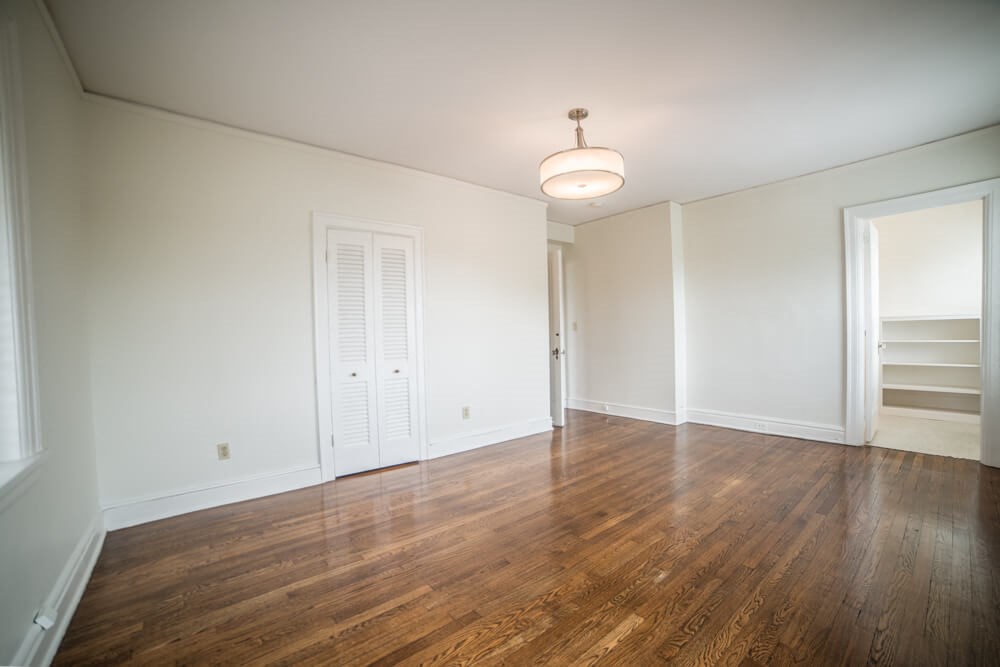 an empty living room with wood floors and white walls