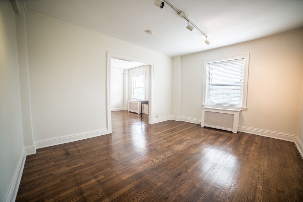an empty living room with wood floors and a window
