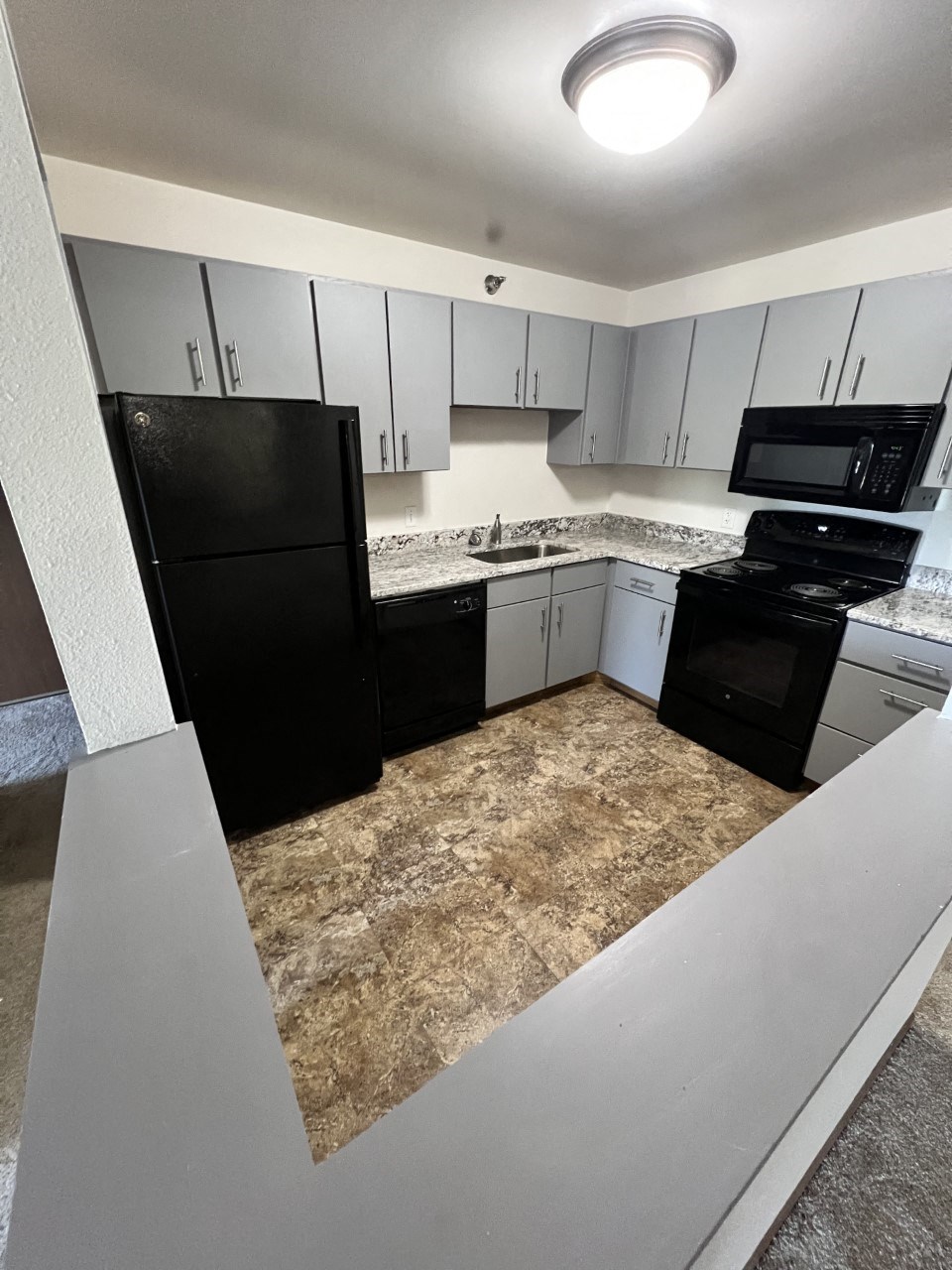 a kitchen with white cabinets and black appliances