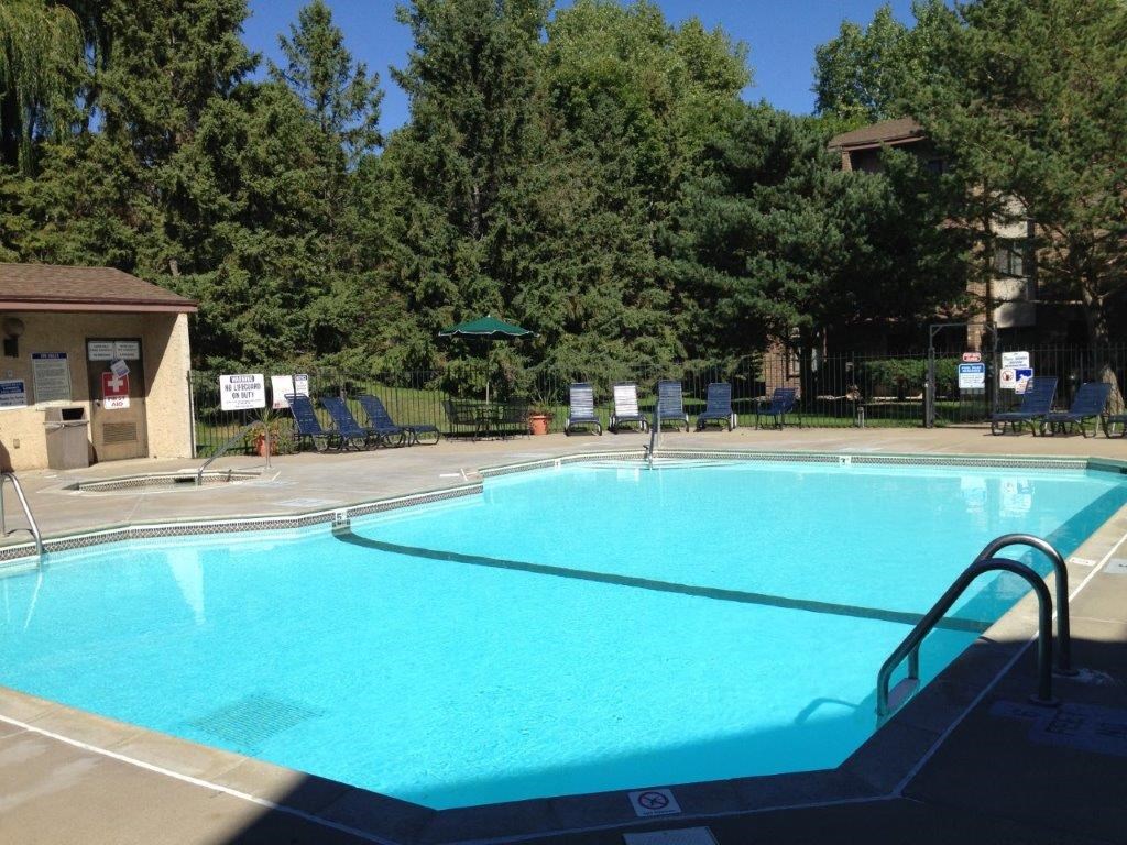 A large swimming pool surrounded by trees and a building.