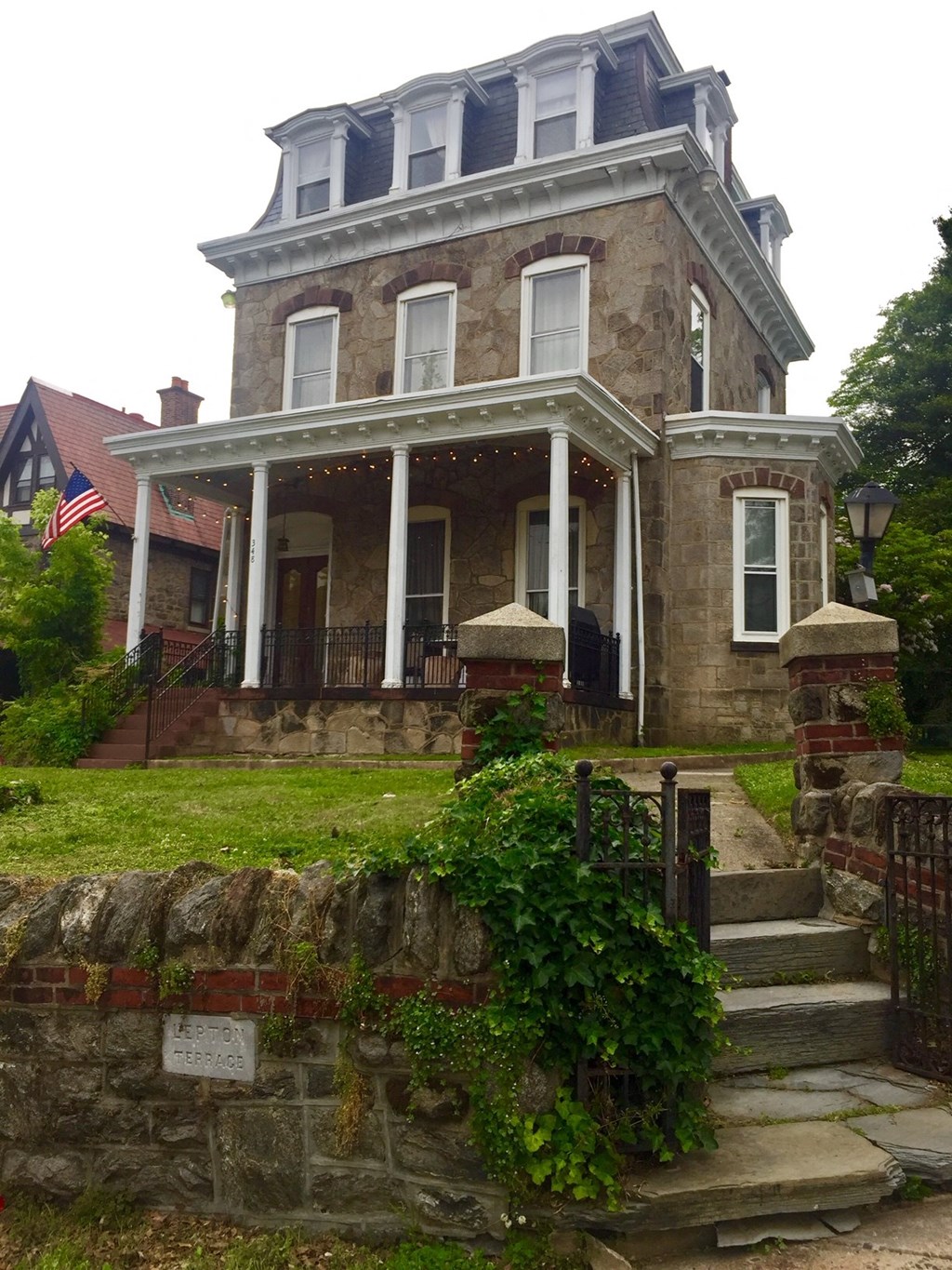 an old house with a porch and a stone wall