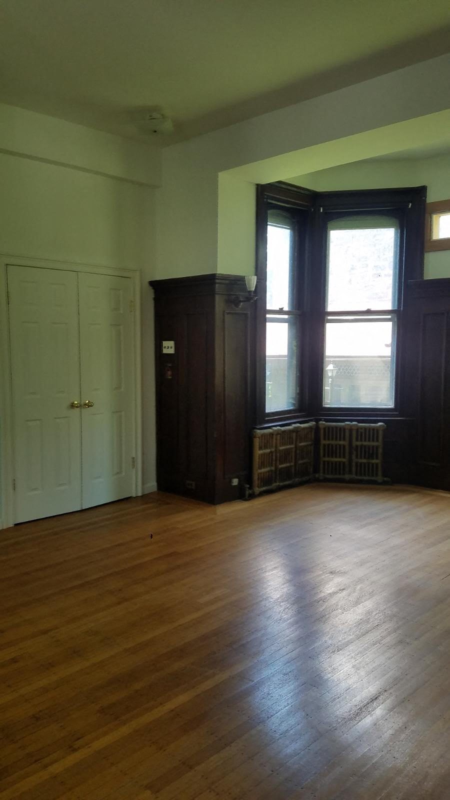an empty living room with wood floors and a window