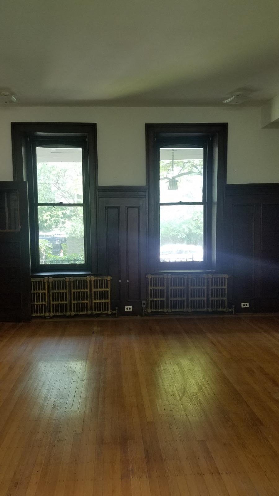 an empty room with wood floors and two windows
