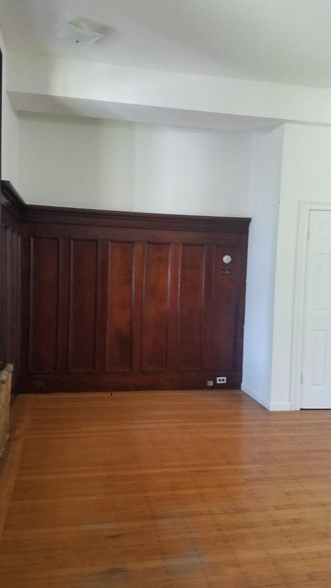 an empty living room with wooden floors and a wooden door