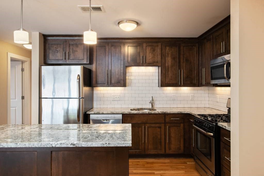 a kitchen with wooden cabinets and marble counter tops