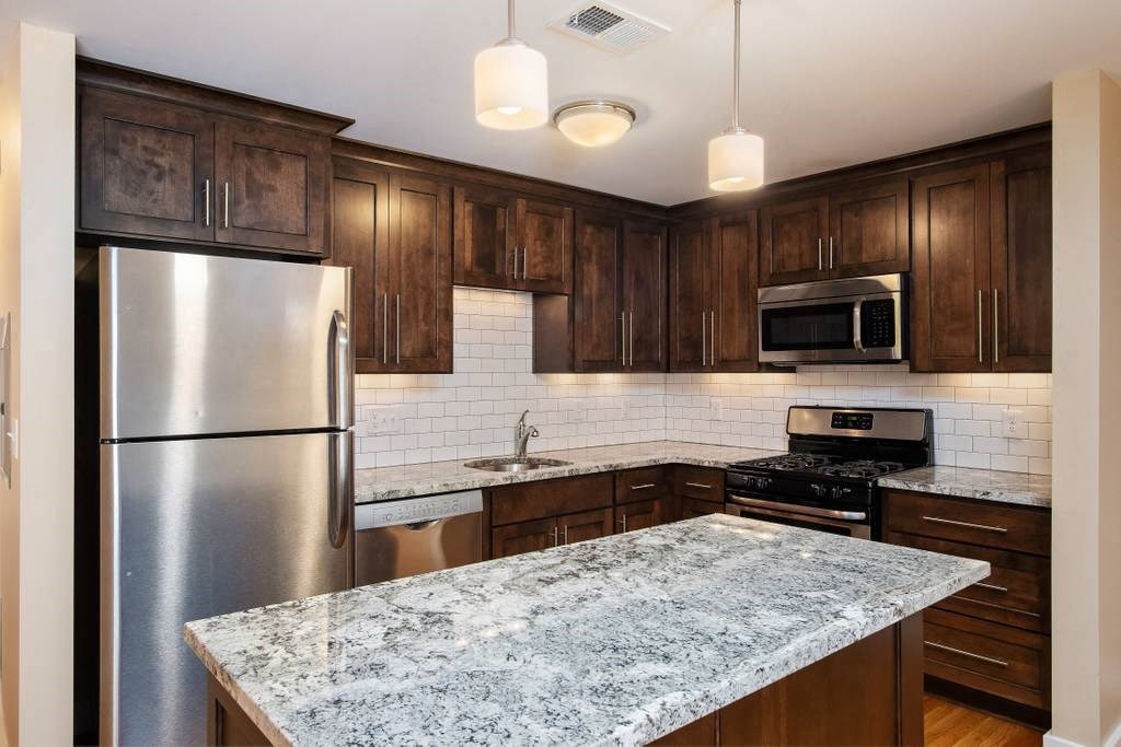 a kitchen with a marble counter top and a stainless steel refrigerator