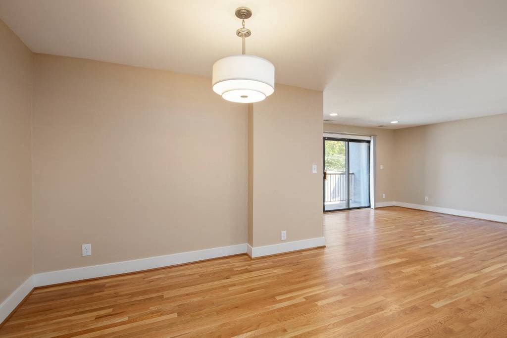 an empty living room with wood flooring and a lamp