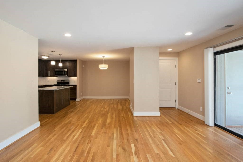 an empty living room and kitchen with wood floors