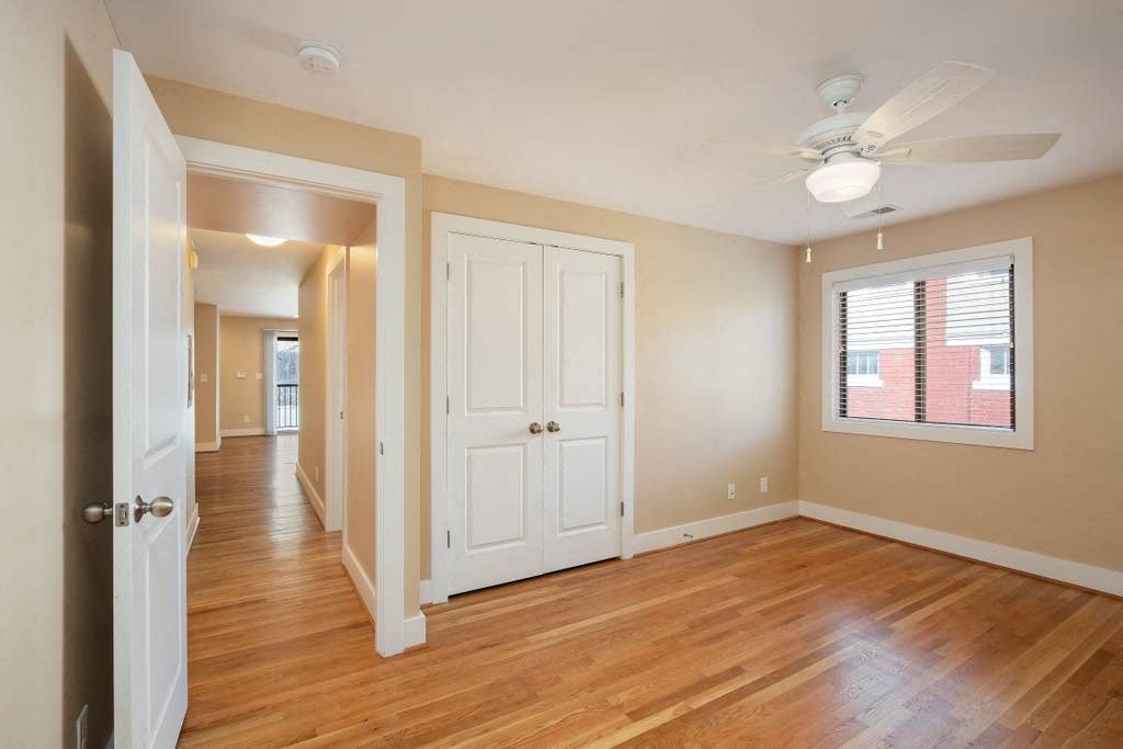 an empty living room with wooden floors and a ceiling fan