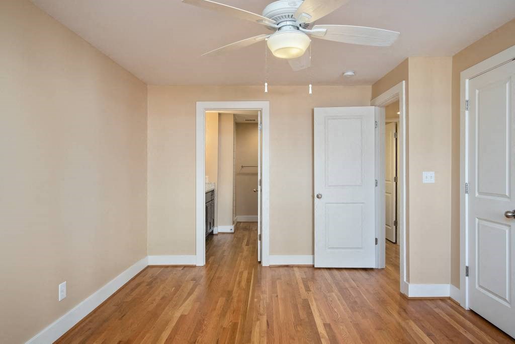 an empty living room with a ceiling fan and a closet