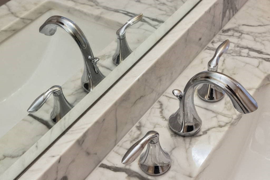 a close up of a bathroom sink with faucets