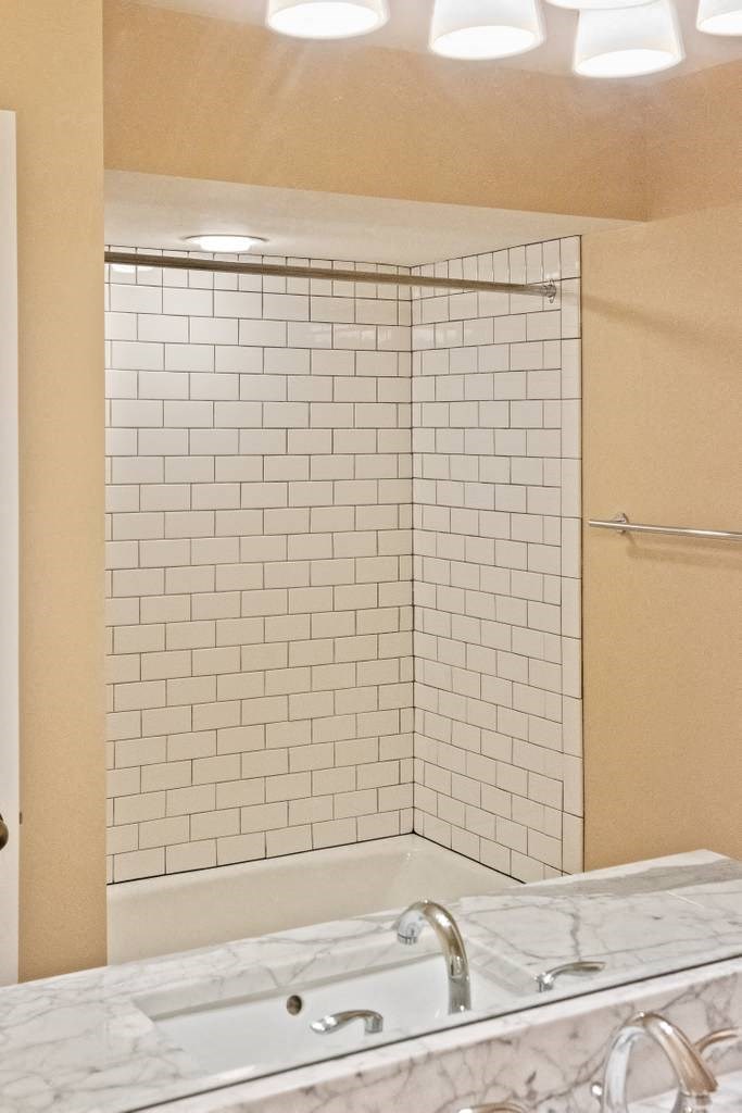 a bathroom with a tub and a shower with white tiles